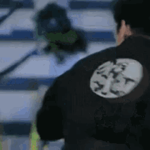 a man wearing a black jacket with a logo on the back .