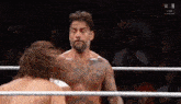 two men are wrestling in a ring and one of them is without a shirt on .