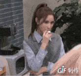a woman in a ponytail eating a sandwich with gif written on the bottom left