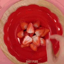 sliced strawberries in a red bowl that says easyplus on the bottom