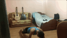 a man is doing push ups in a living room with a guitar on the couch
