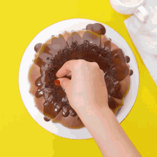 a person 's hand is reaching into a chocolate cake on a white plate