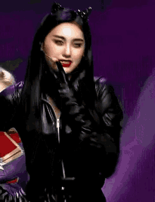 a woman in a catwoman costume is holding a microphone and wearing gloves .