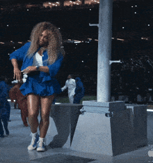 a woman in a blue jacket and shorts is standing next to a pole