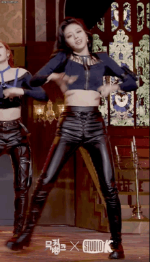 a woman in a blue crop top and black leather pants is dancing