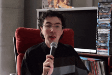a man is sitting in a chair holding a microphone