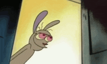 a cartoon rabbit with pink eyes and a purple ear is standing in front of a yellow wall .