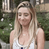 a woman wearing a white tank top with studs and a necklace