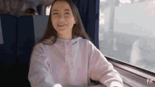 a woman is smiling while sitting in a train car