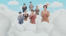a group of young men are standing in the clouds with their hands in the shape of a heart