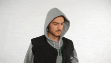 a man wearing a grey hoodie and a black vest with the letter j on it