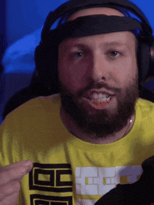 a man with a beard is wearing headphones and a yellow shirt that says bb on the front