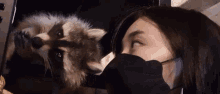 a woman wearing a mask is looking at a raccoon in a microwave .