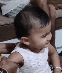 a baby girl in a white dress is smiling and looking at the camera