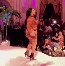 a woman walking down a runway with a crowd watching