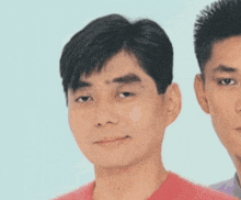 two men are standing next to each other and one of them is wearing a red shirt
