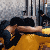 a group of men are huddled together in a locker room and one of them has a tattoo on his arm