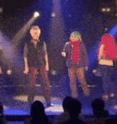 a group of people are standing on a stage in front of a blue light