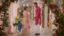 a man and a woman are standing next to each other in a room with flowers .