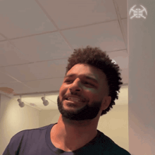 a man with curly hair and a beard is smiling in a room