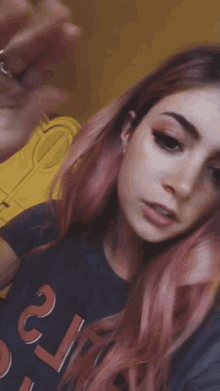 a girl with pink hair is wearing a t-shirt with the letter t on it .