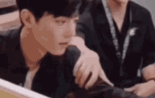 a man is sitting at a table looking at a computer screen .