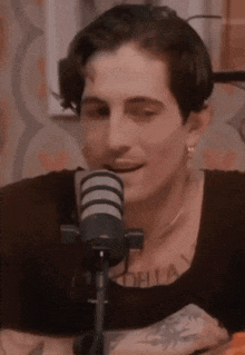 a man is sitting in front of a microphone and talking into it .
