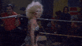 a woman in a leopard print dress is standing in a boxing ring in front of a crowd .