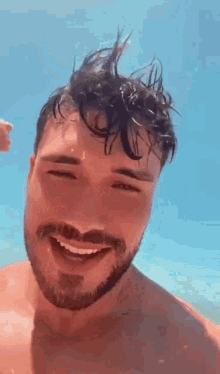 a shirtless man with a beard and mustache is smiling while standing in the water .