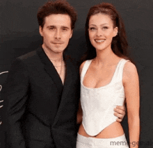 a man in a suit is standing next to a woman in a white top .