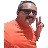 a man wearing sunglasses and an orange shirt giving the peace sign