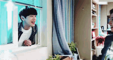 a man is looking out of a window and smiling while another man looks on