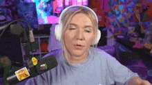 a woman wearing headphones is standing in front of a microphone in a room .