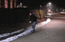 a man walking down a sidewalk at night