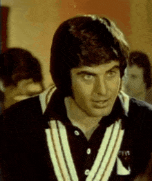 a man wearing a black shirt with a white striped collar and a white stripe on the sleeves