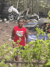 a man wearing a red shirt that says freedom stands in front of a pile of junk
