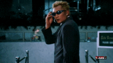 a man in a suit and sunglasses is talking on a cell phone