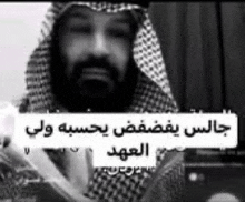 a black and white photo of a man with a beard wearing a keffiyeh and a hood .