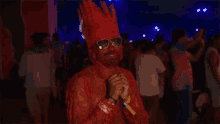 a man in a red costume with a crown on his head stands in a crowd at night