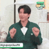 a man wearing a green cardigan and a white shirt with a chanel book in the background