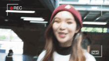 a woman wearing a red beanie is being recorded on a video camera