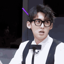 a man wearing glasses and a bow tie has a purple arrow pointing to his head