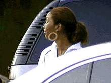 a woman wearing hoop earrings is sitting in a car