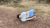 a man is laying on his stomach on the ground in a field .