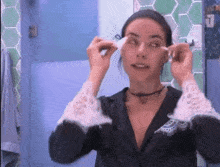 a woman is looking at herself in the mirror while cleaning her face .