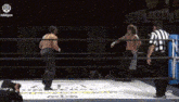 two men are wrestling in a ring while a referee looks on .