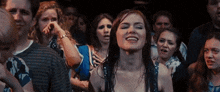 a woman in a crowd of people is smiling and making a funny face