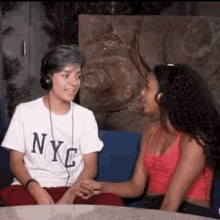 a boy and a girl are sitting on a couch holding hands and talking .