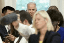 a man in a suit is standing in a crowd of people looking at the camera .
