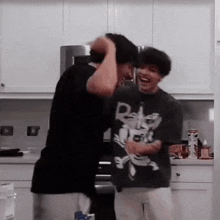 two men are standing next to each other in a kitchen laughing .